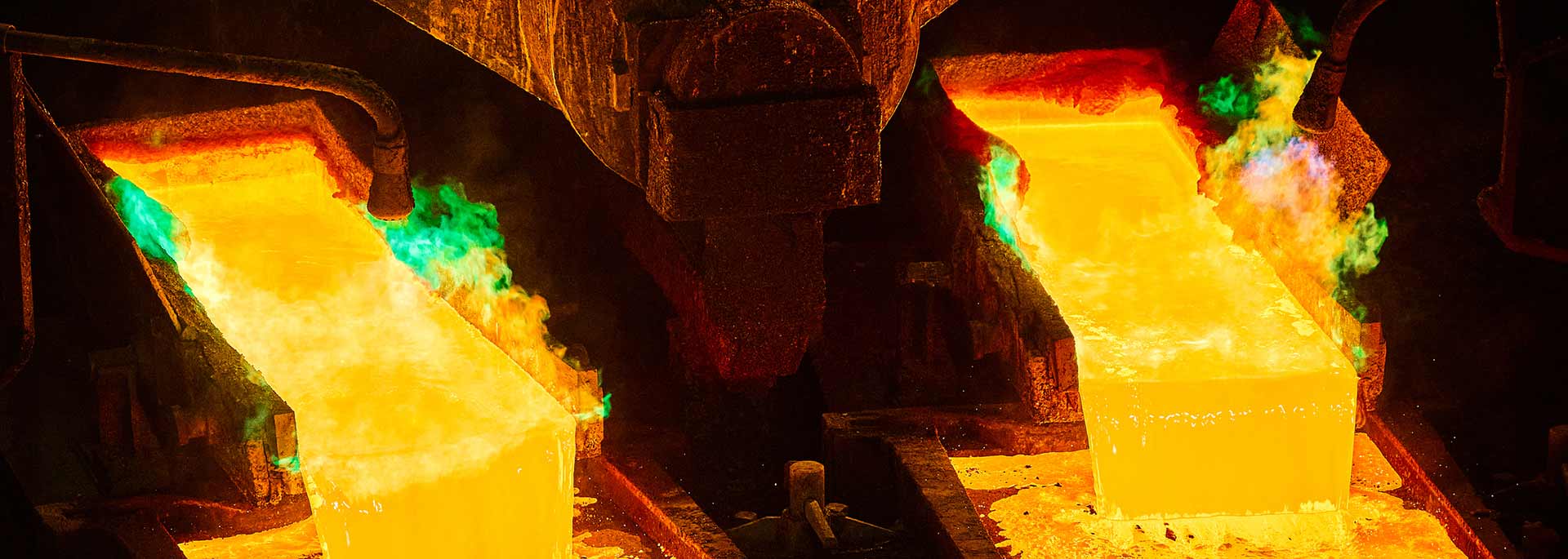 Two buckets of bright molten steel pouring into containers.