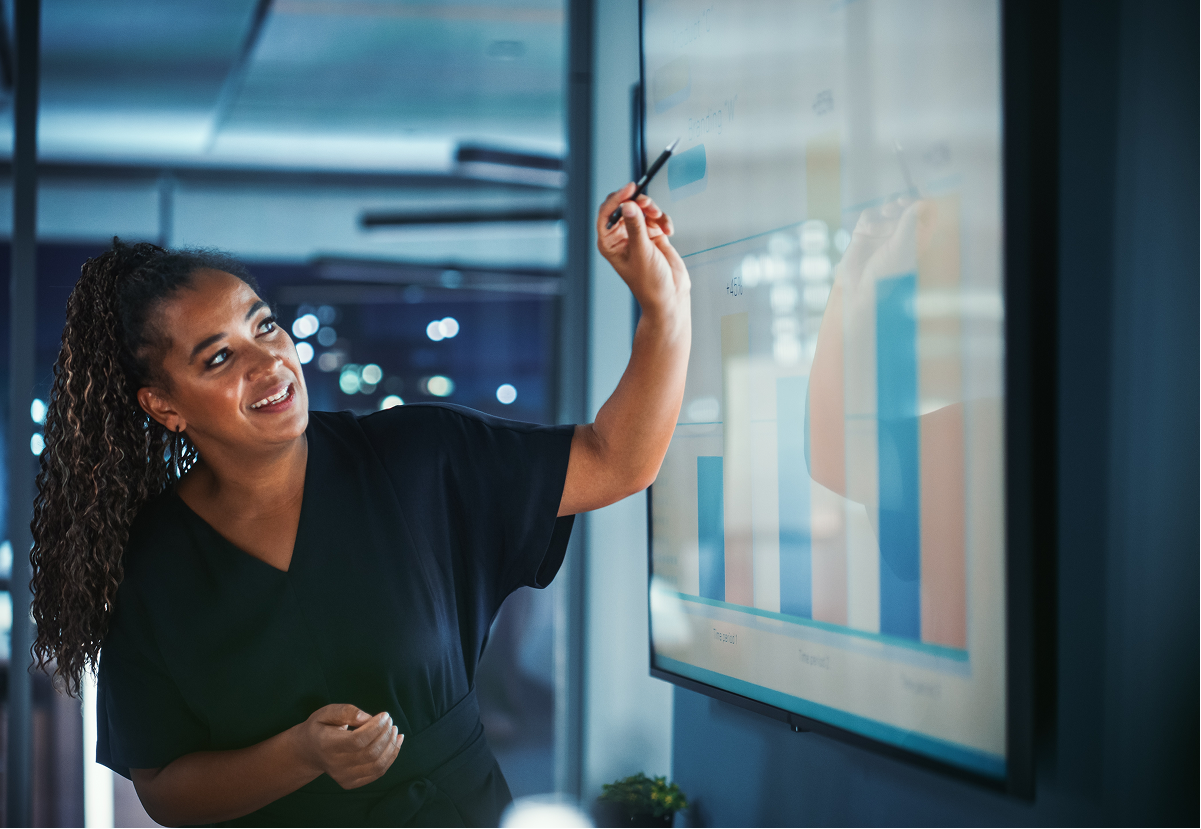 A woman pointing at a chart and smiling 
