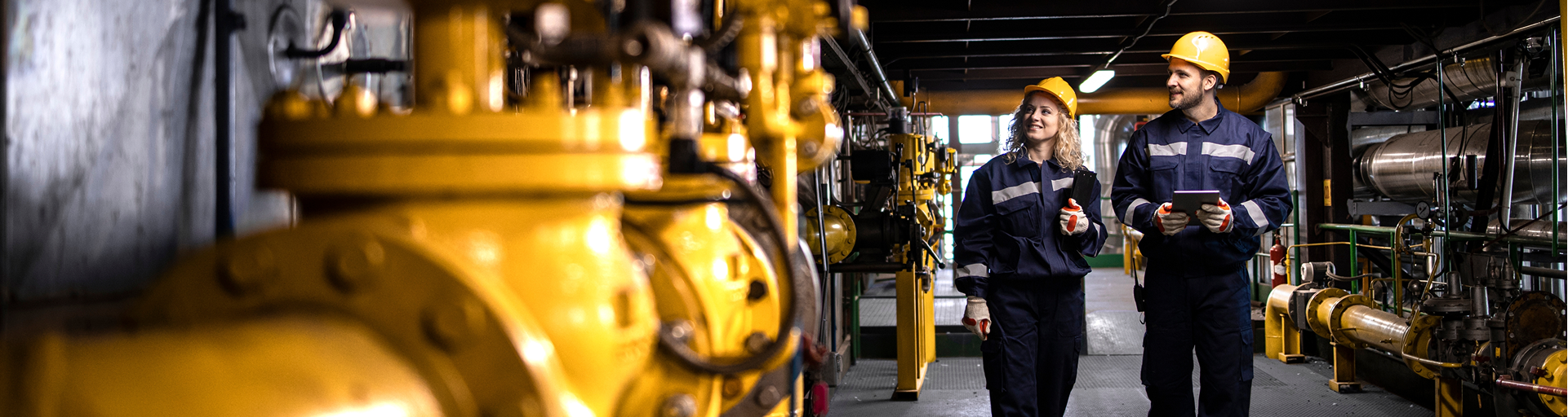 Engineers in hard hats walk through a manufacturing facility