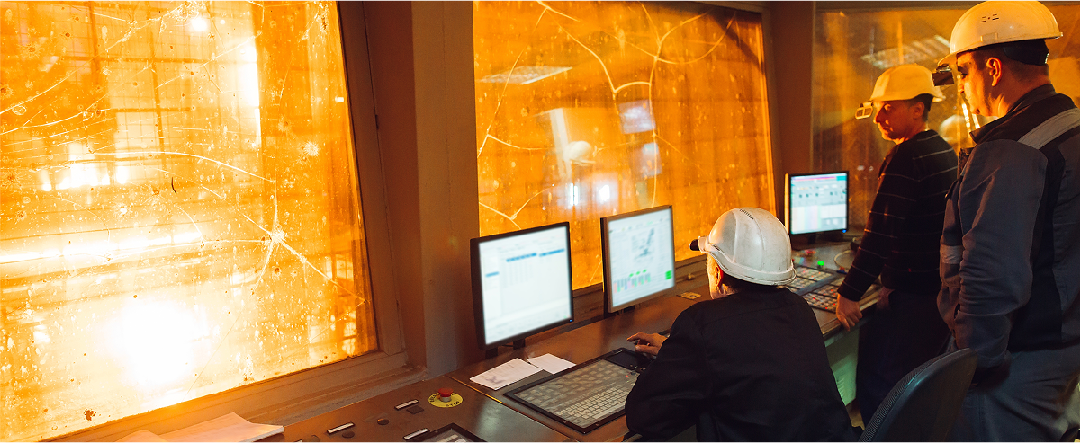 People in a metal processing control room monitor high-temperature industrial operations.